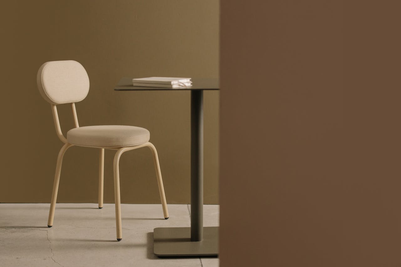 Elegant minimalist setup with a beige chair and table against a warm background.